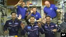 FILE - In this image taken from video from NASA, astronauts, front row from left, Kimiya Yui, of Japan, Oleg Kononenko, of Russia, and Kjell Lindgren, of the United States, wave after they boarded the International Space Station, July 23, 2015. The three crew members boarded a Russian Soyuz capsule on Friday for an express ride back to Earth.