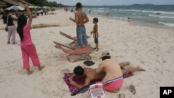 FILE-A Cambodian woman gives massage to a tourist on the beach of Sihanoukville, some 185 kilometers (115 miles) southwest of Phnom Penh, Cambodia, file photo. (AP Photo/Heng Sinith)