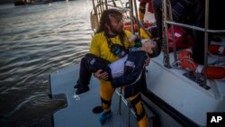 A volunteer carries a young boy after a boat with refugees and migrants sank while crossing the Aegean Sea from Turkey to the Greek island of Lesbos, Oct. 28, 2015. 