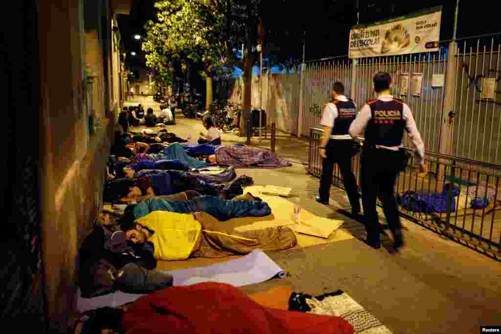 Catalan Mossos d&#39;Esquadra officers walk while parents camp out at the entrance of the occupied Reina Violant elementary school, one of the designated polling stations, before the banned Oct. 1 independence referendum in Barcelona.