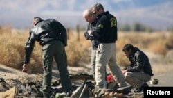 Investigators from the National Transportation Safety Board (NTSB) look at wreckage from the crash of Virgin Galactic's SpaceShipTwo near Cantil, California, Nov. 2, 2014. 