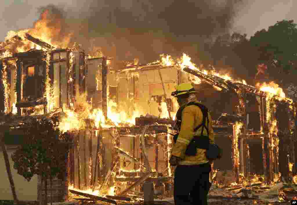 A firefighter monitors a house burning in Santa Rosa, Calif., Oct. 9, 2017. 