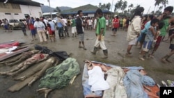 Residents pass by bodies recovered from flashflood in New Bataan, Compostela Valley province, southern Philippines, December 5, 2012.