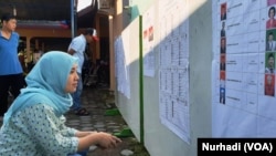 Seorang pemilih memeriksa daftar legislatif yang dipasang di sebuah TPS di Sleman, DIY dalam Pemilu 2019. (Foto: VOA/ Nurhadi)