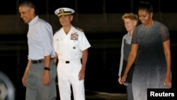 U.S. President Barack Obama, left, and first lady Michelle Obama, right, are greeted by U.S. Navy Admiral Harry Harris and his wife, Bruni Bradley upon the Obamas' arrival at Joint Base Pearl Harbor-Hickam in Honolulu, Hawaii, Dec. 19, 2015. 