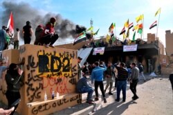 FILE - Pro-Iranian militiamen and their supporters light a fire during a protest in front of the U.S. Embassy in Baghdad, Iraq, Jan. 1, 2020.