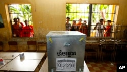 柬埔寨上届大选期间，一些年轻人在首都金边一处投票站对着投票箱拍照(2013年7月28日)