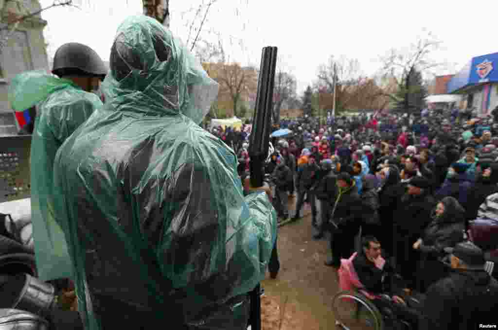 A pro-Russian armed man stands guard at a barricade in front of pro-Russian protesters near the police headquarters in Slovyansk, April 13, 2014.&nbsp;