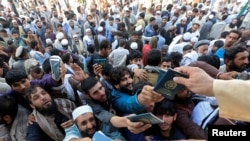 Afghan men wait to collect tokens needed to apply for the Pakistan visa, in Jalalabad, Afghanistan, Oct. 21, 2020. 
