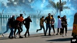 Anti-government protesters run as security forces fire tear gas to disperse them during a clash in Baghdad, Iraq, Jan. 26, 2020. 