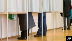 FILE - People fill their ballot papers in voting booths at a polling station in Tallinn, Estonia, March 1, 2015. Estonia has moved away from traditional balloting, with online voting under way for next month's general election, amid tight protective measures. 