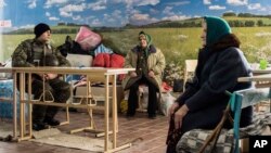 FILE - A Ukrainian soldier, left, guards as two elderly women wait to get a humanitarian aid in Avdiivka, eastern Ukraine, Feb. 5, 2017. 