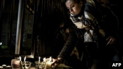 A student lights a candle outside the Saint-Exupery high school in Lyon, France, during a commemorative gathering after two students from the school and a Ukrainian man were killed in an avalanche at Les Deux Alpes ski resort in the French Alps, Jan. 13, 2016.