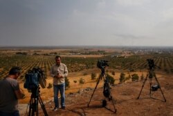 FILE - Journalists work on a hilltop in Ceylanpinar, Sanliurfa province, southeastern Turkey, covering Ankara's incursion into Syria, Oct. 20, 2019.