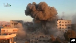 In this image taken from video obtained from the Shaam News Network, which has been authenticated based on its contents and other AP reporting, smoke billows amid buildings at a bomb explosion in Daraya, near Damascus, Oct. 15, 2013. 