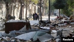 ជន​ស៊ីវិល​ដើរ​កាត់​កម្ទេច​កម្ទី​នៃ​អគារ​នៅ​ក្នុង​តំបន់​ដែល​កាន់កាប់​ដោយ​ក្រុម​ឧទ្ទាម​ក្នុង​ក្រុង Aleppo ប្រទេស​ស៊ីរី កាលពី​ថ្ងៃទី១៤ ខែវិច្ឆិកា ឆ្នាំ២០១៦។