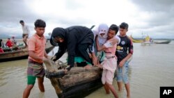 Warga Bangladesh membantu dua perempuan Rohingya turun dari kapal setelah melewati kanal di Shah Porir Deep, di Teknak, Bangladesh, 31 Agustus 2017.