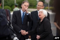 US Treasury Secretary Janet Yellen (R) shakes hands with US Ambassador to China Nicholas Burns (L) as Yang Yingming, Director General of the Department of International Economic Relations of China's Ministry of Finance, looks on after Yellen arrived at Be