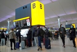 FILE - Travelers queue with their luggage in the departures hall at Terminal 2 of Heathrow Airport in west London on Dec. 21, 2020, as a string of countries around the world banned travelers arriving from the UK.