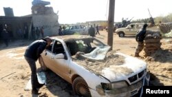 A man looks at a damaged car near a military base in Barsis, some 50 km (30 miles) outside Benghazi, after a suicide bomber detonated a truck packed with explosives at an army checkpoint, Dec. 22, 2013. 