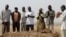 A family gathers around the grave, where three murdered family members were buried together, in Jos in Nigeria's Plateau state, December 28, 2011. Armed Fulani herdsmen shot dead three members of a family in an attack in Nigeria's ethnically and religious