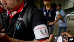 FILE - A local journalist wears an arm band supporting press freedom as he gathers with other journalists during the court appearance of a newspaper editor and a columnist at a township court.