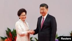 Pemimpin Hong Kong Carrie Lam berjabat tangan dengan Presiden China Xi Jinping setelah dia mengucapkan sumpah jabatan pada peringatan 20 tahun penyerahan kota tersebut dari pemerintah Inggris kepada China, di Hong Kong, China, 1 Juli 2017. (REUTERS/Bobby Yip).