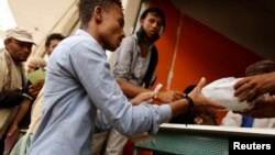 FILE - A man displaced from Yemen's Red Sea city of Hodeidah receives a food ration at a charity food distribution in Sana'a, Yemen, July 3, 2018.