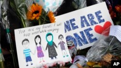 A message card is placed at a collection of flowers left at the Botanical Gardens in Christchurch, New Zealand, March 16, 2019. 