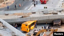 Petugas penyelamat mencoba mengeluarkan kendaraan-kendaraan yang terjebak di bawah jembatan penyeberangan yang ambruk saat sedang dibangun di Belo Horizonte, Brazil (3/7). 