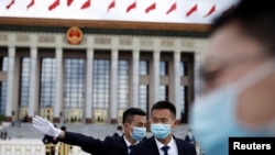 预防病毒传播和减少感染新冠病例，戴口罩可能比保持社交距离或者禁足在家都更为重要。中国保安在正在举行中国人大会议的北京人大会堂外站岗。（路透社2020年5月25日资料照）