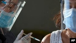 Seorang petugas kesehatan menginokulasi seorang wanita dengan vaksin Sinovac COVID-19 China di pusat vaksinasi sementara di Manila, Filipina, 22 Juni 2021. (AP Photo/Aaron Favila, File)