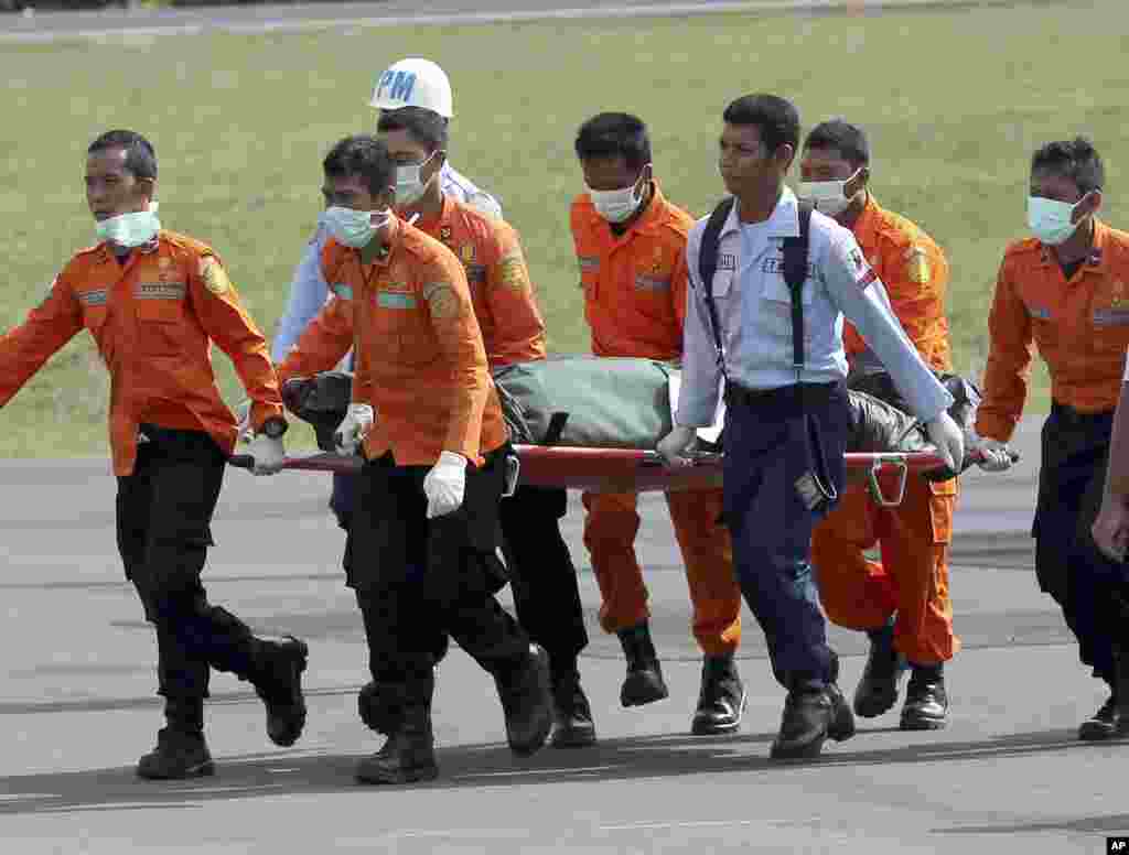 National Search and Rescue Agency (BASARNAS) personnel carry the body of a victim on board the ill-fated AirAsia Flight 8501, from a helicopter upon arrival at the airport in Pangkalan Bun, Indonesia, Jan. 1, 2015. 