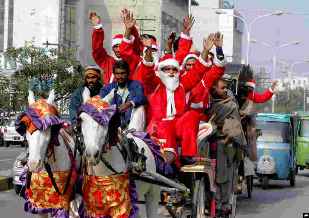 Orang-orang berpakaian Sinterklas mengendarai kereta kuda sebelum perayaan Natal di Lahore, Pakistan (23/12). Meski umat Kristiani adalah minoritas di Pakistan, Natal merupakan libur nasional dan dirayakan di seluruh negeri. (AP/K.M. Chaudary)