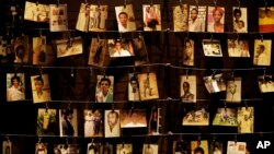 FILE - Family photographs of some of those who died hang on display in an exhibition at the Kigali Genocide Memorial centre in the capital Kigali, Rwanda, April 5, 2019. 