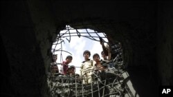 Anak-anak mengintip ke lubang akibat serangan udara yang dipimpin Saudi di jembatan di Sana'a, Yaman, 23 Maret 2016.