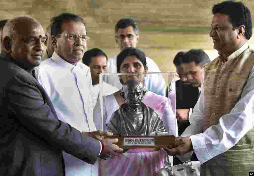 Sri Lankan President Maithripala Sirisena (second from left) and his wife Jayanthi Sirisena, receive a bust of Mahatma Gandhi during their visit to Rajghat, the memorial to the late Mahatma Gandhi, in New Delhi, Feb. 16, 2015.
