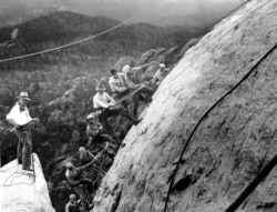 FILE - Sculptor Gutzon Borglum, left, directs drillers as they work on the head of President George Washington at the Mount Rushmore Memorial in the Black Hills area near Keystone, South Dakota, July 22, 1929.