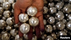 Seorang pegawai PT Timah menunjukkan bola-bola timah olahan di Pangkal Pinang. (REUTERS/Beawiharta)