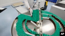 FILE - Laboratory technician at a Sanofi-Pasteur production plant manufacturing Panenza, Val-de-Reuil, western Paris.