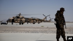 FILE - A NATO soldier stands guard under the wing of a C-130 Hercules aircraft, that belongs to the Afghan National Army, in Kandahar Air Field, Afghanistan, Aug. 18, 2015. 