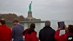 FILE - Tourists view the Statue of Liberty during a ferry ride to Liberty Island in New York, Nov. 5, 2015. A U.N. official predicts the U.S. will lose millions of dollars as tourists will shun the country due to the Trump administration's controversial immigration and travel restrictions.