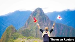 Japanese tourist Jesse Katayama holds Peruvian and Japanese flags after becoming the first tourist to visit the ruins of Machu Picchu during the COVID-19 pandemic, in Machu Picchu, Peru, Oct. 13, 2020.
