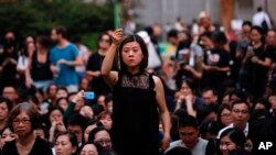 A woman holds a flower as she joins hundreds of mothers protesting against the amendments to the extradition law after Wednesday's violent protest in Hong Kong on Friday, June 14, 2019. (AP Photo/Vincent Yu)