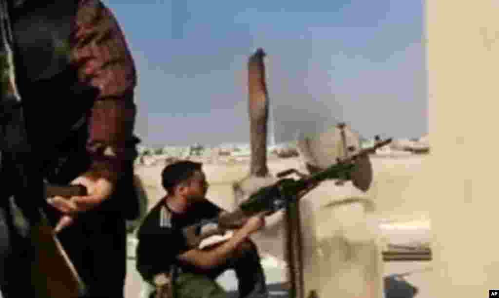 This image made from amateur video released by the Ugarit News shows a Free Syrian Army solider firing his weapon during clashes with Syrian government troops in Aleppo, Syria, July 24, 2012.