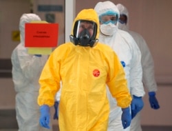 Russian President Vladimir Putin, center, wearing a protective suit enters a hall during his visit to the hospital for coronavirus patients in Kommunarka settlement, outside Moscow, Russia, March 24, 2020.