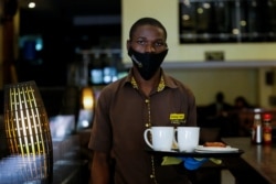 FILE - John Brian, an employee at Cafe Deli Restaurant delivers an order during the reopening after weeks of lockdown restrictions amid the coronavirus disease (COVID-19) outbreak, along Kenyatta avenue in Nairobi, June 11, 2020.