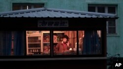 지난해 11월 북한 평양의 한 식료품점 판매원이 휴대전화를 사용하고 있다.