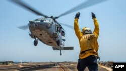 FILE - A sailor directs an MH-60S Sea Hawk helicopter aboard the guided-missile destroyer USS Bainbridge, Aug. 8, 2019, in Persian Gulf waters. 