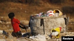 An unemployed man pulls a trolley full of recyclable waste material, which he sells for income, in Daveland near Soweto, South Africa, Aug. 4, 2015.